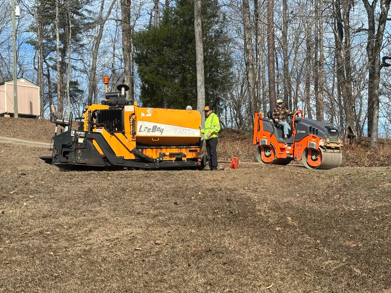 Asphalt paving equipment and crew on a broad paved surface